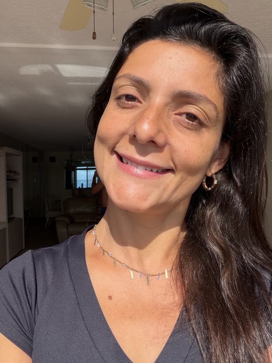 Adriana Ricci em retrato próximo, em casa, com sorriso contido.